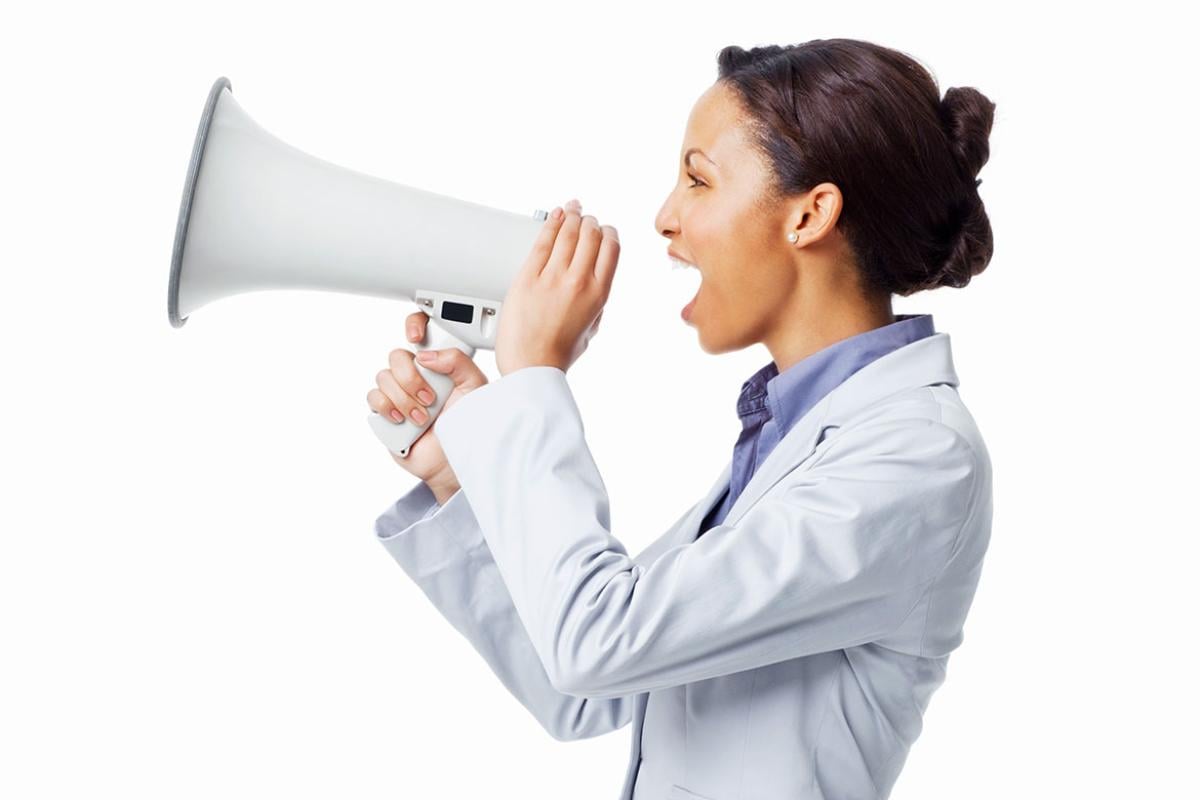 A doctor in profile speaking through a white megaphone against a white background.