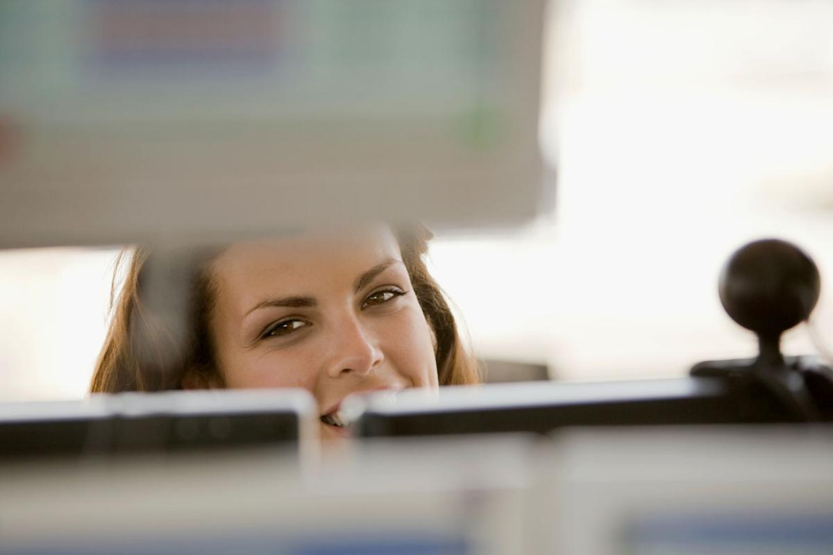 Smiling person behind a computer screen