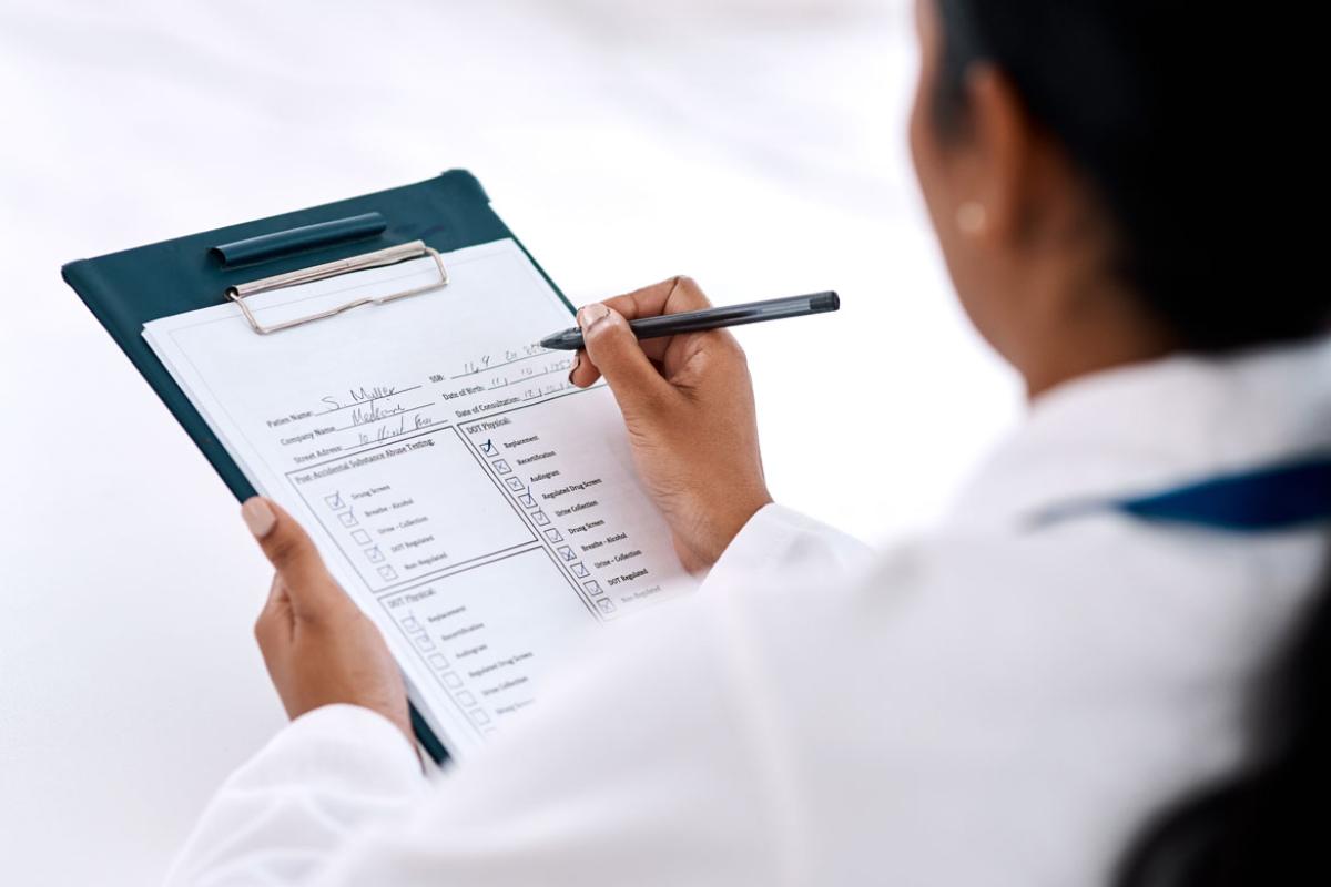 View over a doctor's shoulder as they look at a form on a clipboard.
