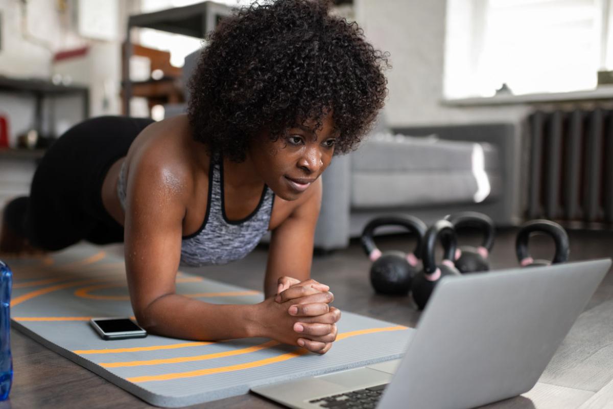 Woman watching work out video from a yoga mat