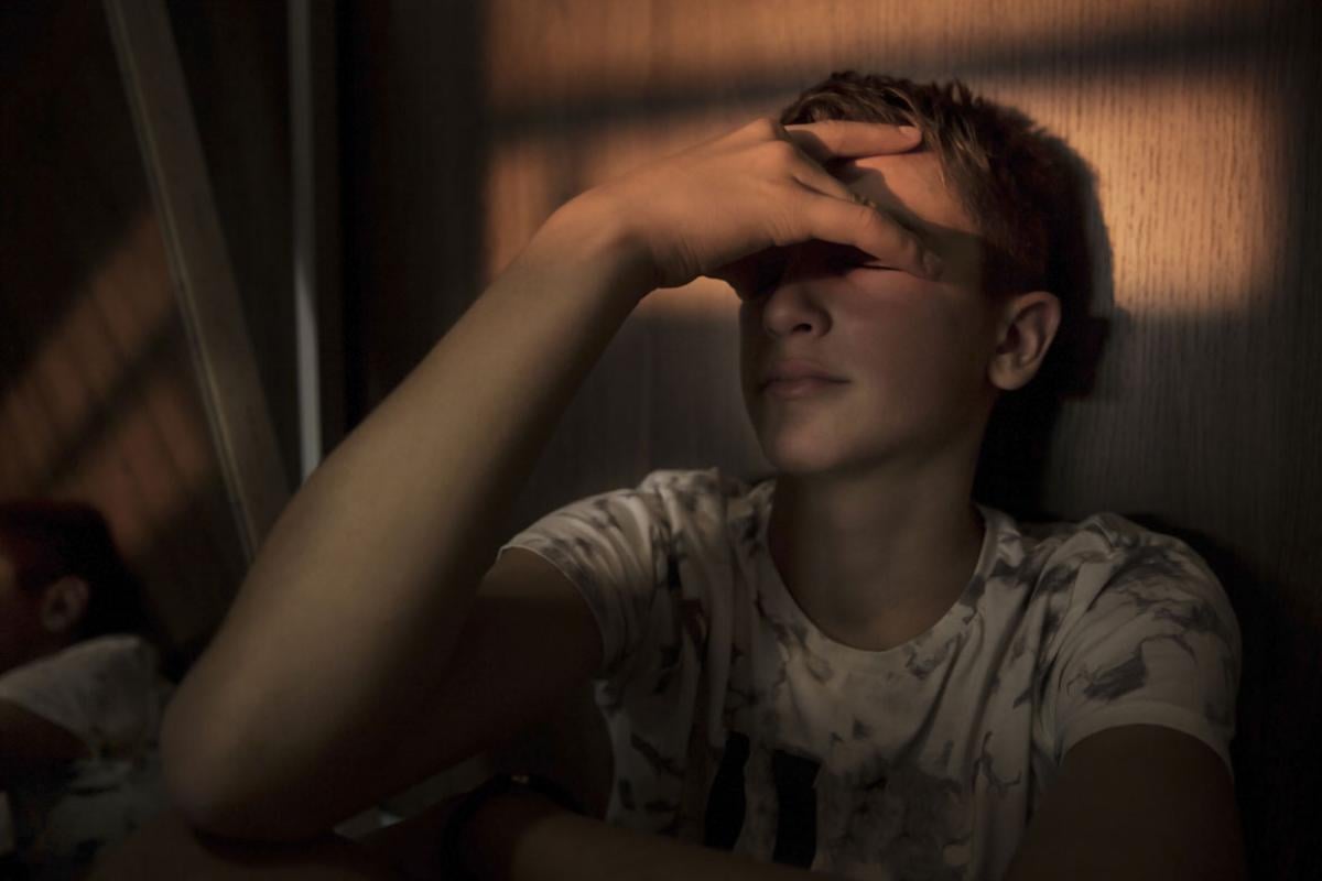 Young person sitting in a dark room