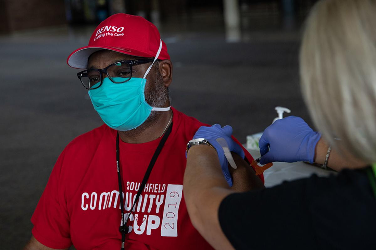Man wearing a mask gets a vaccine from a health worker