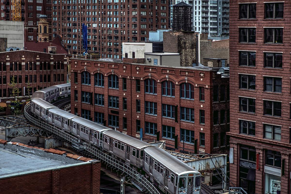 An elevated/subway train rounding a curve next to some city buildings