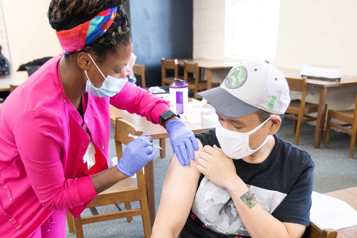 Health care worker vaccinating a young teen at Oak Grove High School, Hattiesburg Clinic Community Vaccination Program