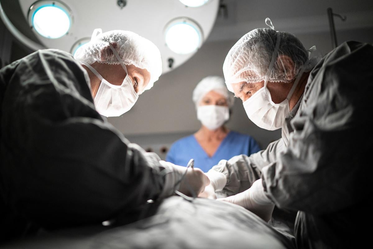 Surgeons and a nurse in an operating room working on a patient