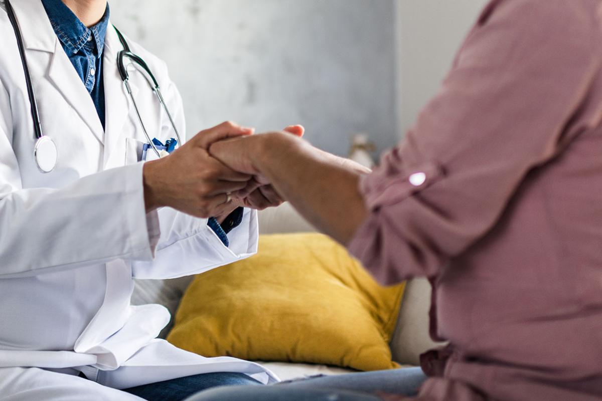 Physician and patient holding hands