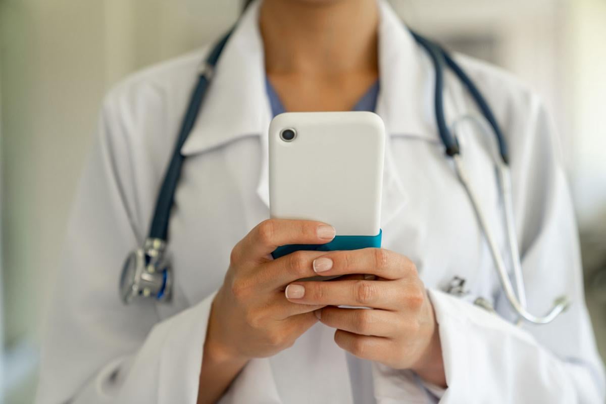 Health care worker holding a smartphone with two hands