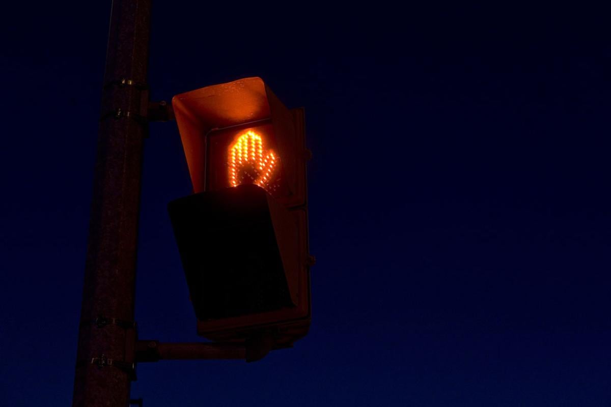 Lit "don't walk" hand sign icon at road intersection 