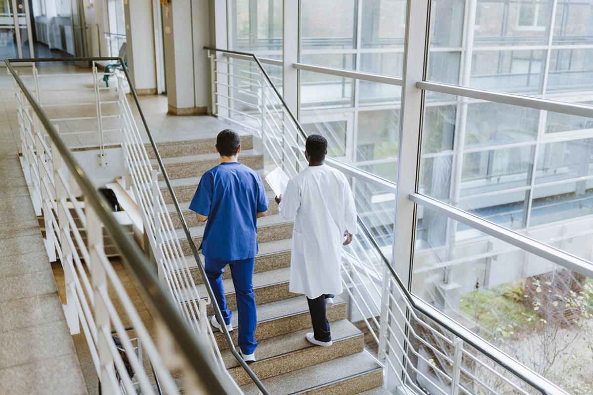 Two health care workers walking up a flight of stairs