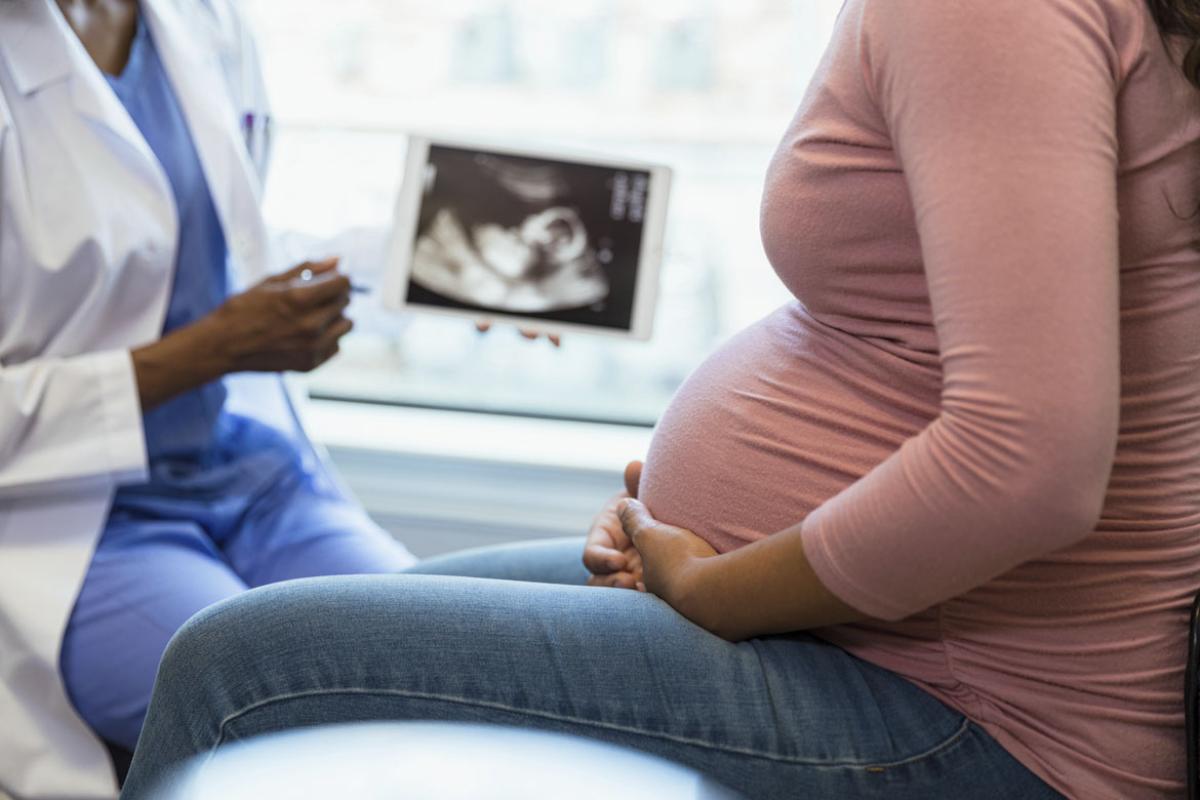 Doctor shows pregnant patient an ultrasound on a digital tablet