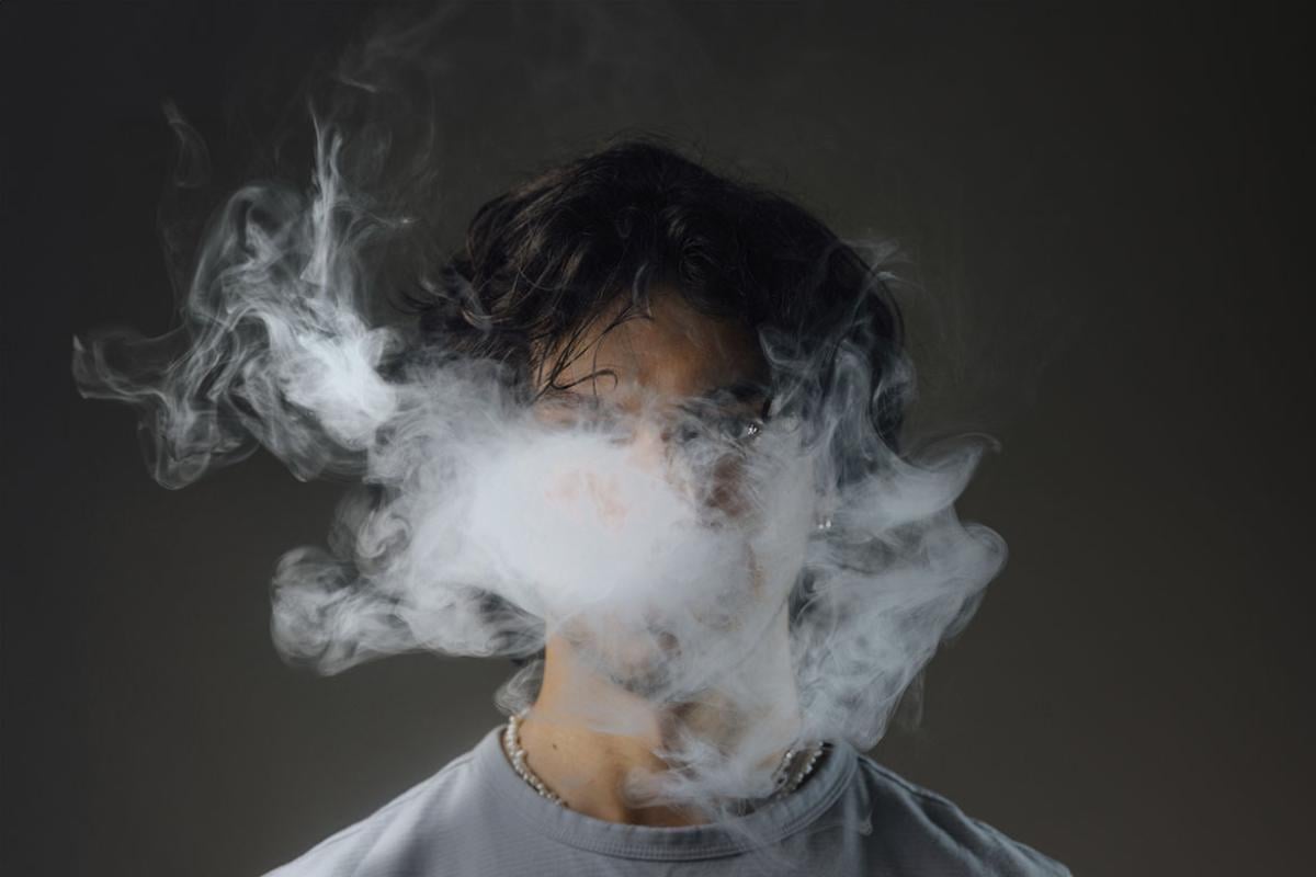 Young adult male with vape smoke obscuring his face