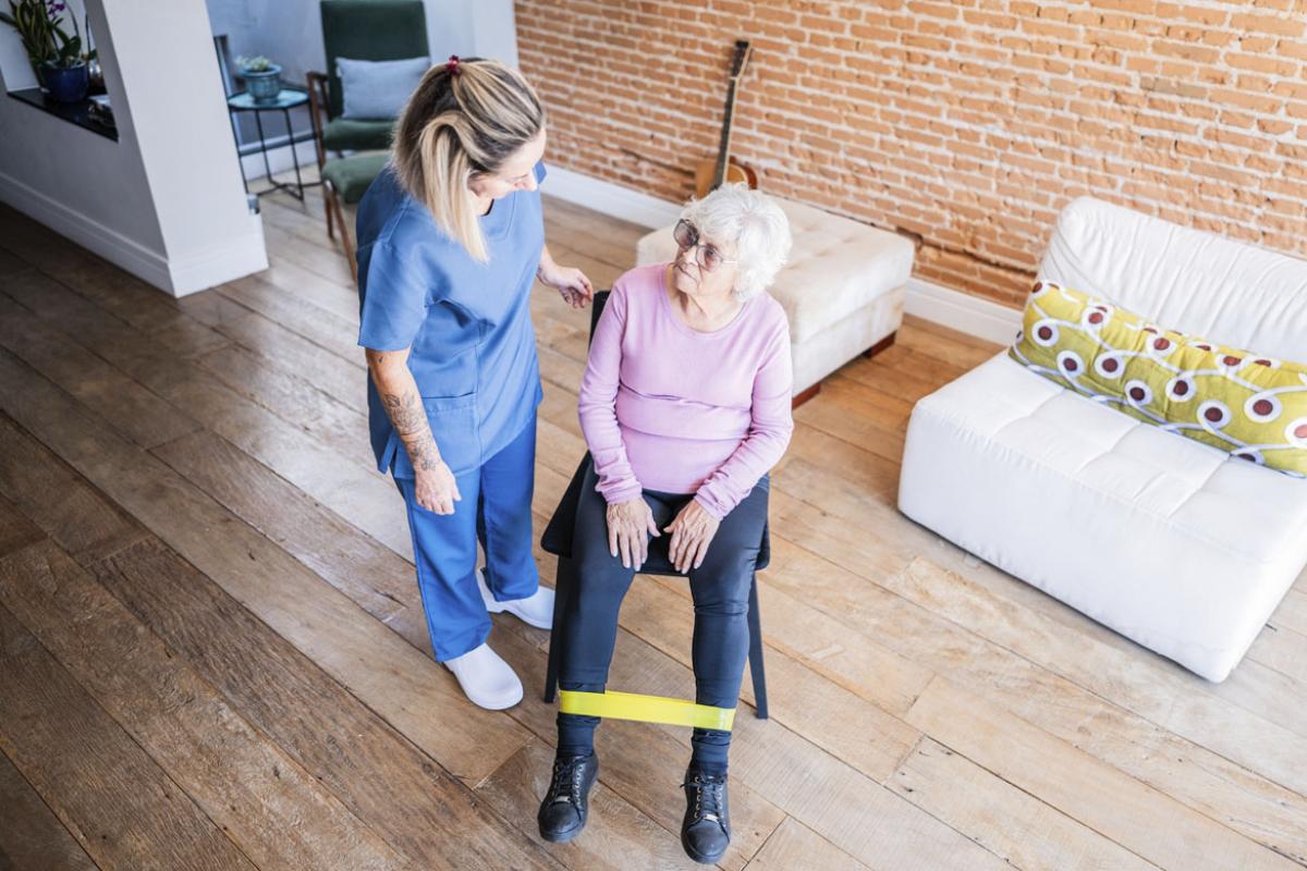 Senior patient and physical therapist doing exercises during house call