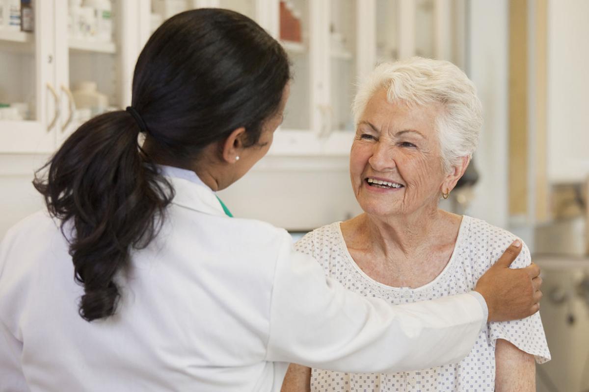 Physician places hand on smiling patient's shoulder