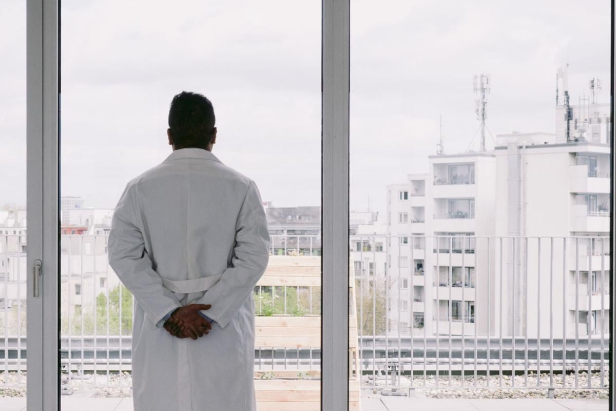 Solitary physician looking out a window