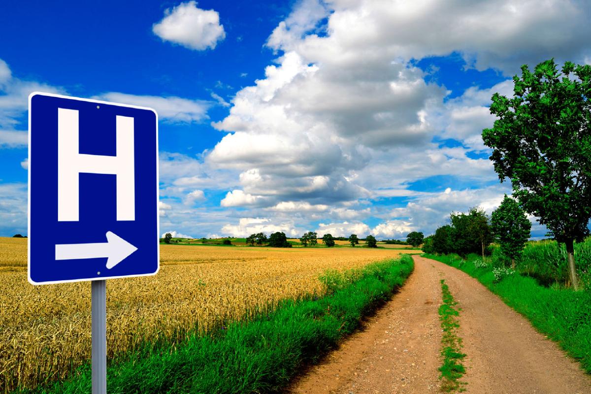 Hospital sign pointing down rural highway.