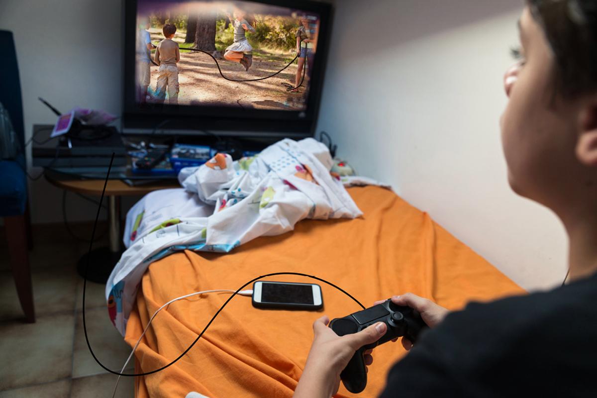 Boy sitting in bedroom playing video games.