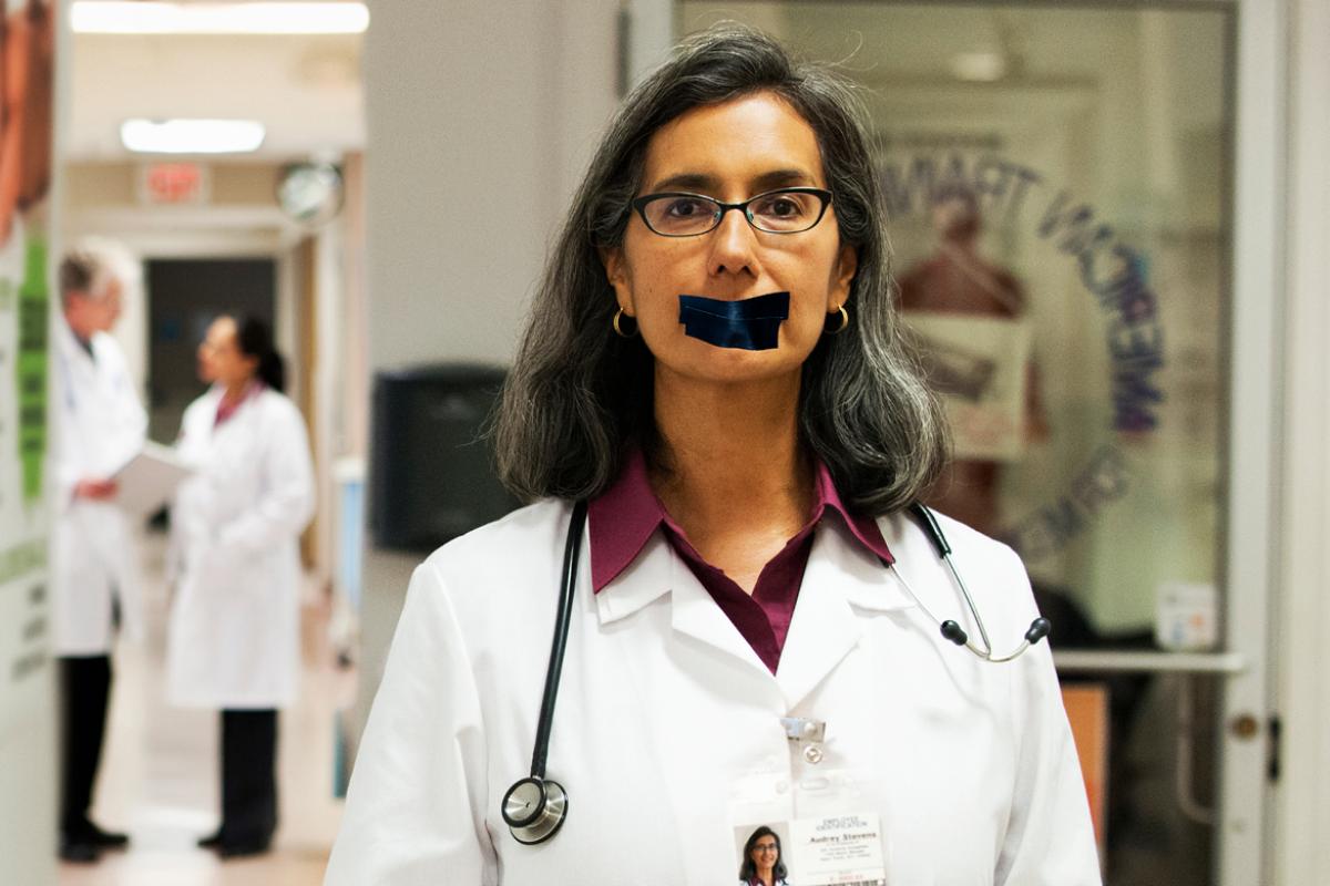 Physician with black tape covering her mouth