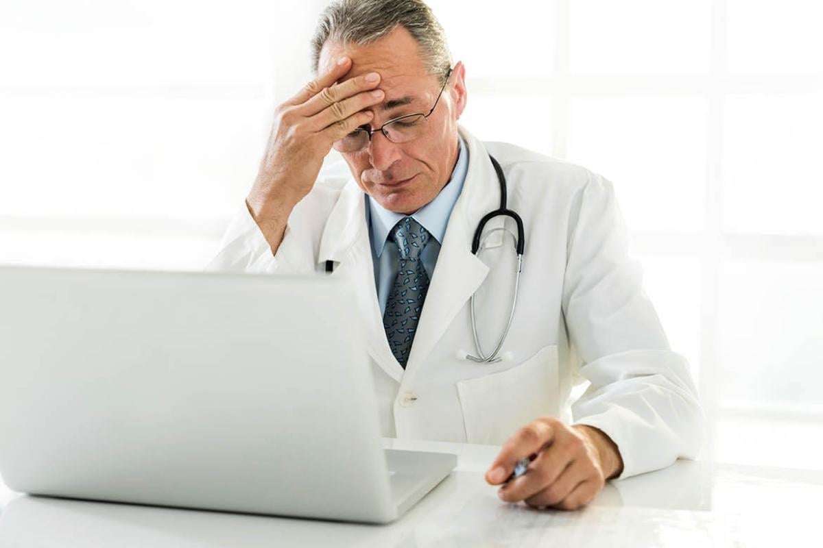 Distraught physician works with computer. 