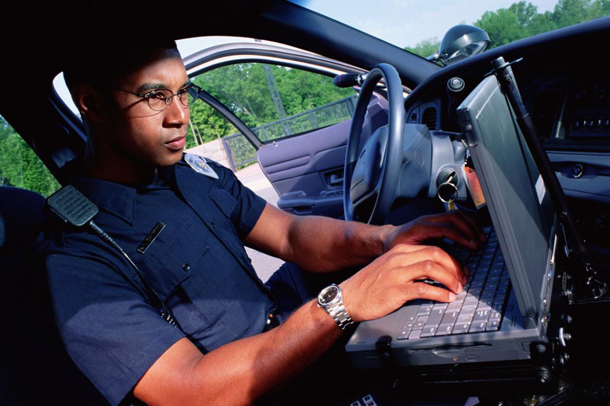 Police officer using laptop in his vehicle. 