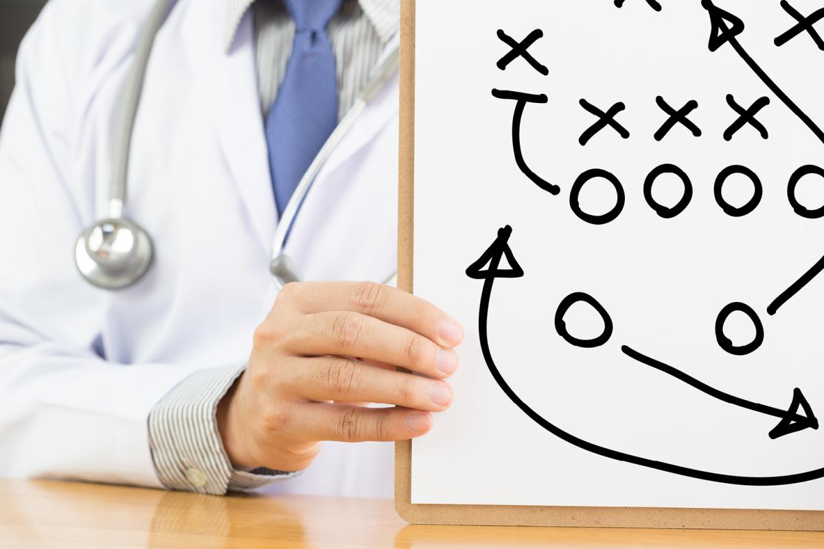 Physician holding up a football play chart.  