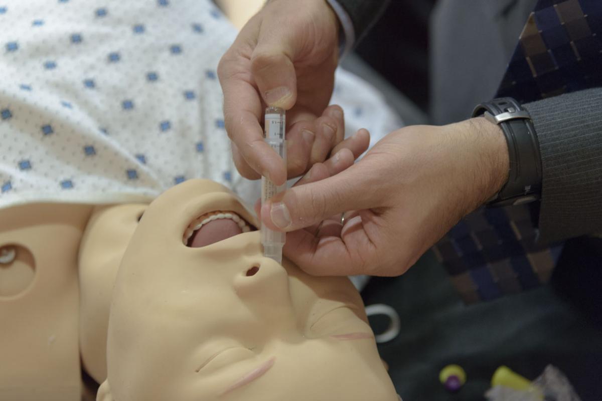 Tech demonstrates how to administer naloxone on training mannequin. 