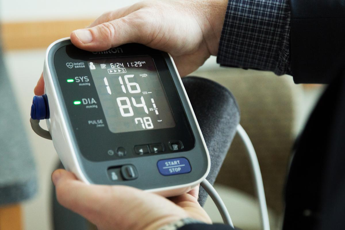 Man holding an electronic blood pressure measuring device. 