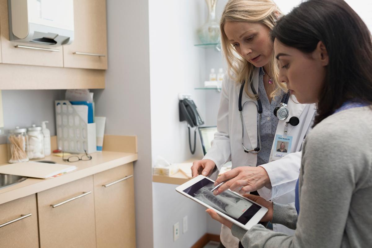 Physician shows a patient an x-ray on a digital tablet. 