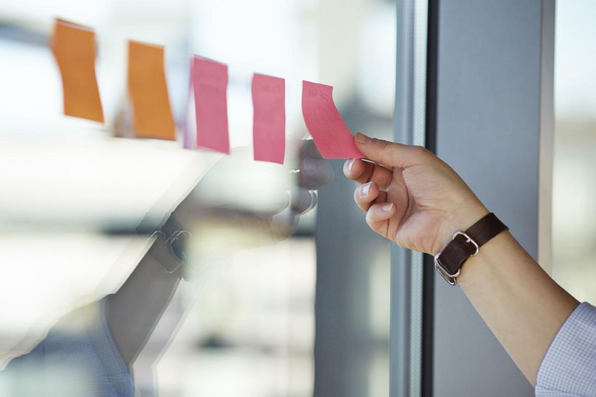 Hand removing post-its from a window. 