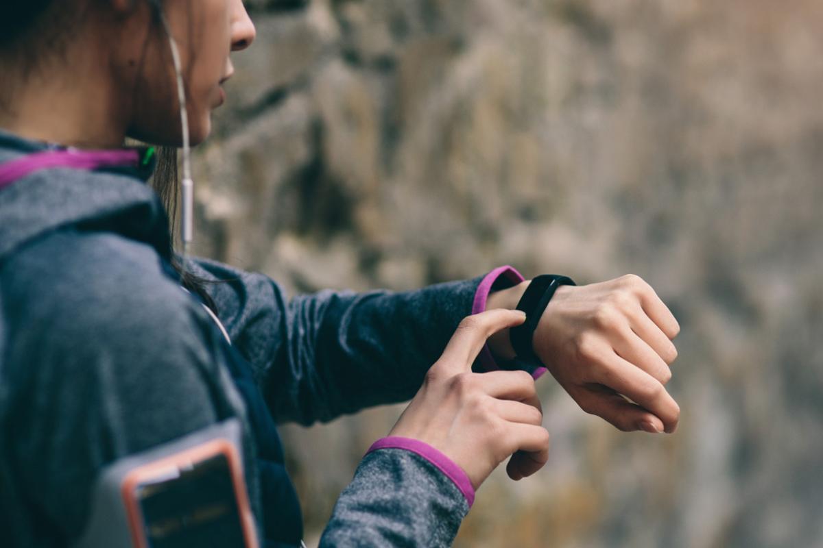 A female runner checks her fitness tracker to see how her workout is going. 