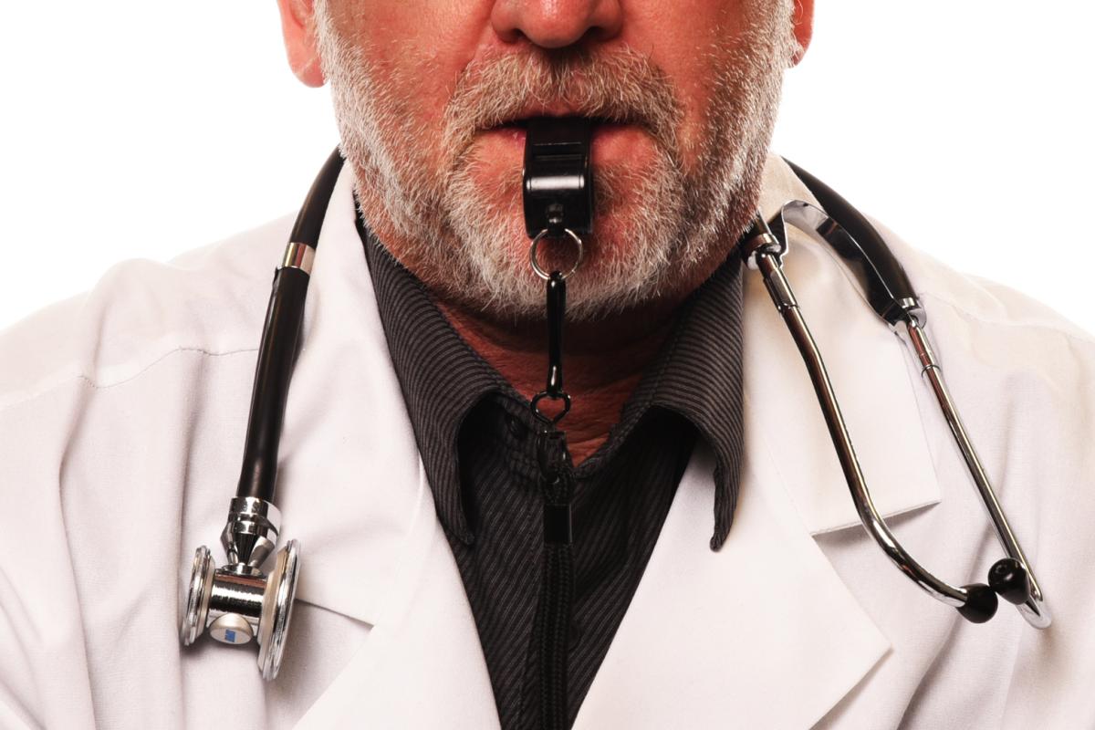 A doctor with a stethoscope around his neck and a whistle in his mouth