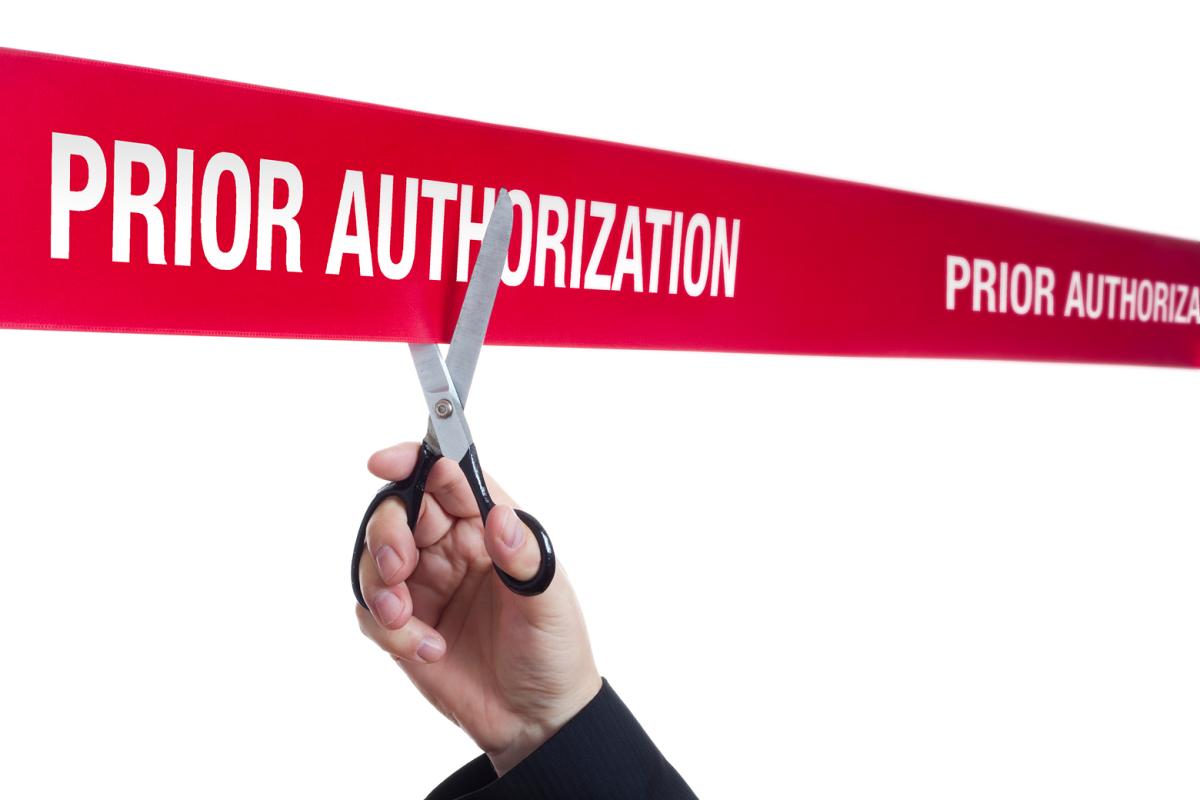 A pair of scissors preparing to cut a ribbon that says prior authorization.