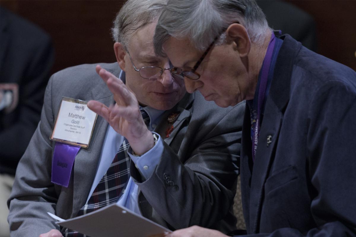 Two AMA delegates discuss an issue at a meeting. 
