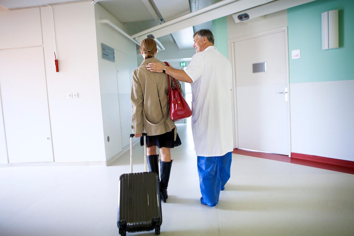 Person with suitcase and medical professional touching their shoulder