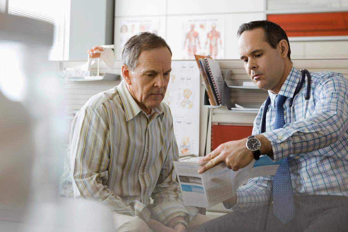 Physician explains information in medical pamphlet to patient.
