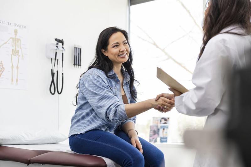 Smiling patient shakes hands with physician