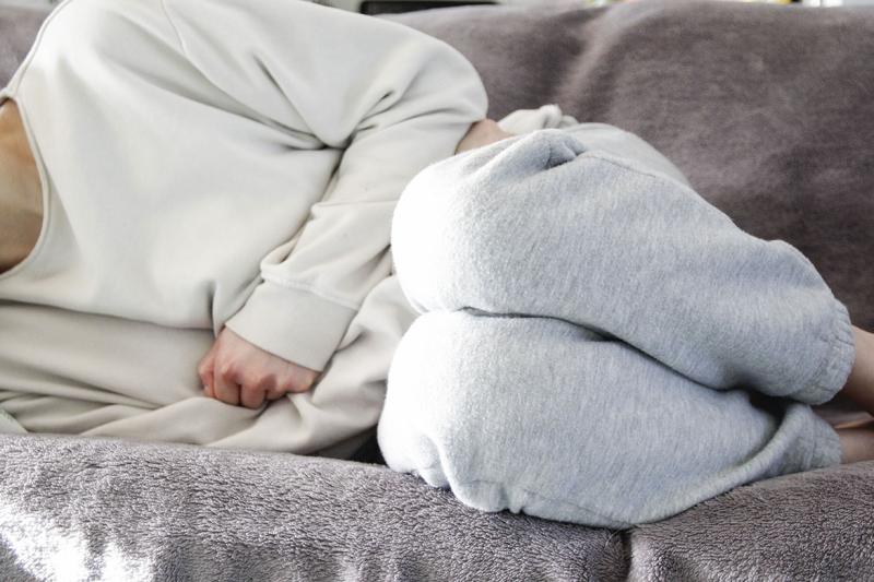 Woman on couch clutches midsection